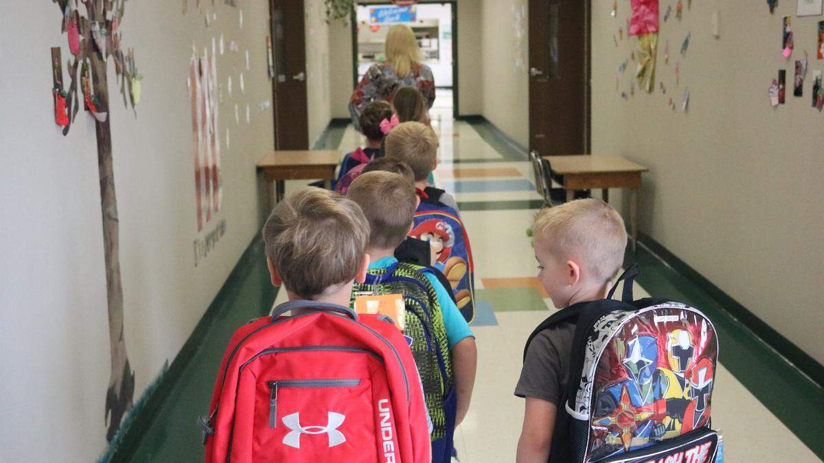 A line of kindergarteners walk behind their new teacher Mrs. Brenda Grigg on their way to the start of their first day of school at Alhambra Primary School.