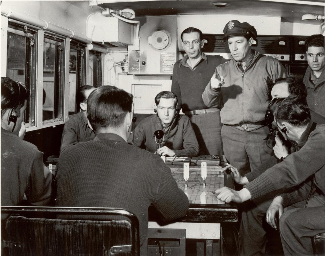 Maj. Gen. Elwood R. “Pete” Quesada, 9th Tactical Air Force commander, European Theater of Operations, points a finger to emphasize a point in a control van of mobile radar equipment, March 1945. On a large table map, technicians plot data picked up by radar equipment. In close operations, such as those which immediately preceded Victory in Europe (VE) Day, this type of mobile radar proved invaluable.