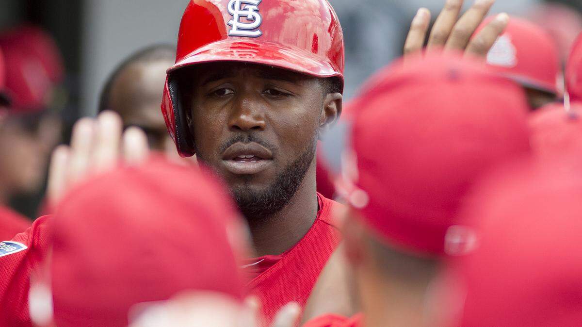 Outfielder Dexter Fowler gets rounds of high fives in the dugout after scoring a run during a spring training game in Jupiter, Florida.