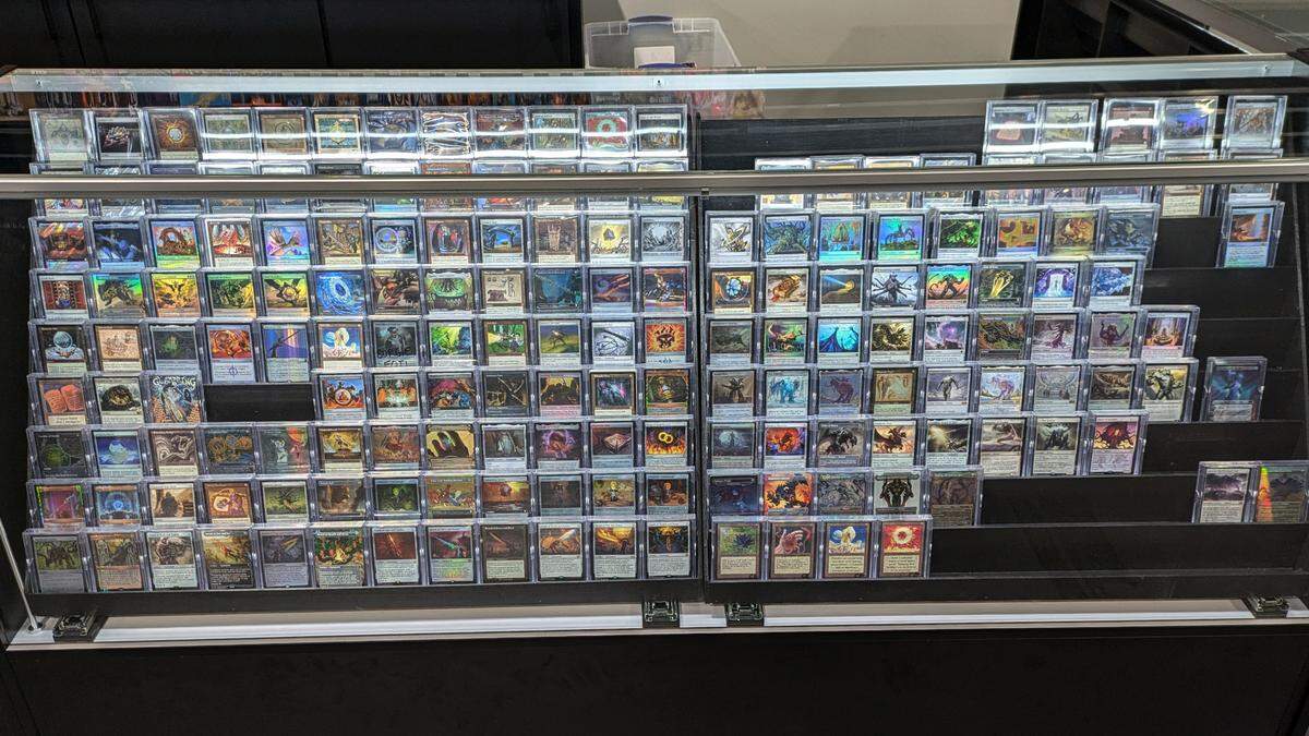 Individual trading cards showcased in custom-built display cases at Impact Gaming Center