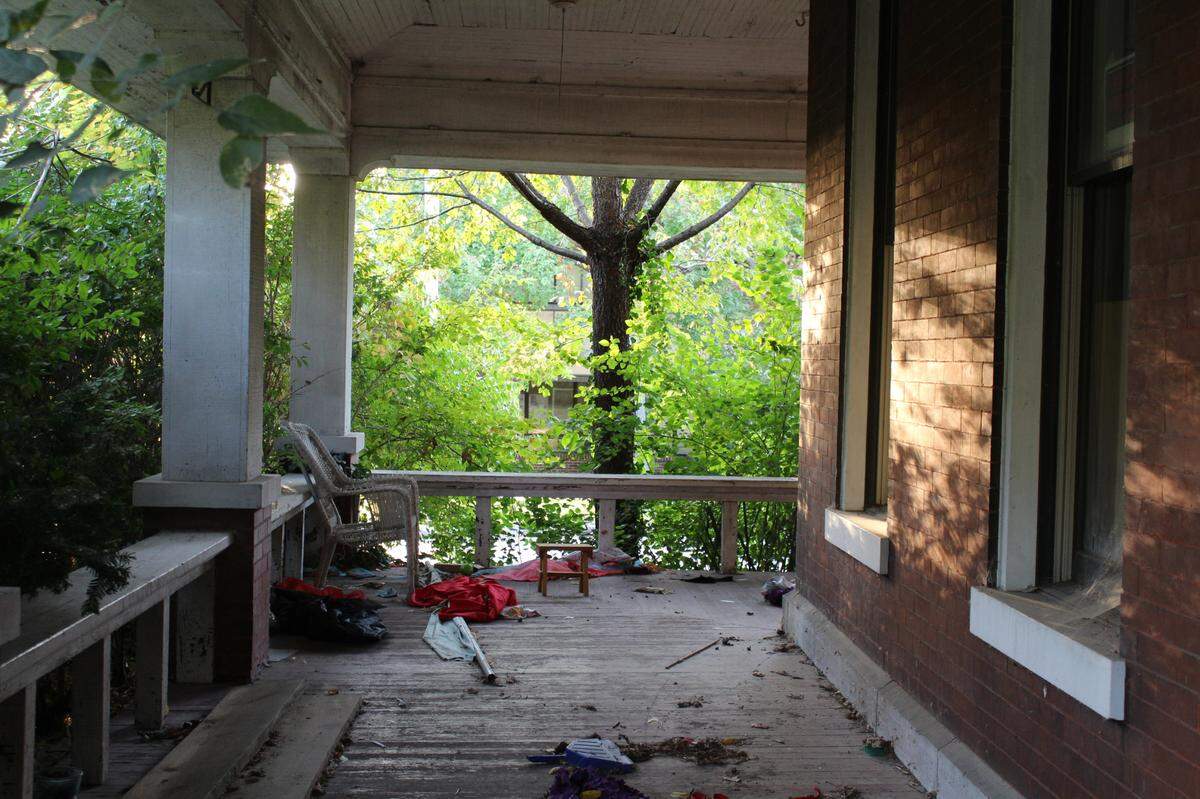 A stool, fabric and other trash left by squatters litter the wraparound porch of a historic home at 107 E. D St. near downtown Belleville.