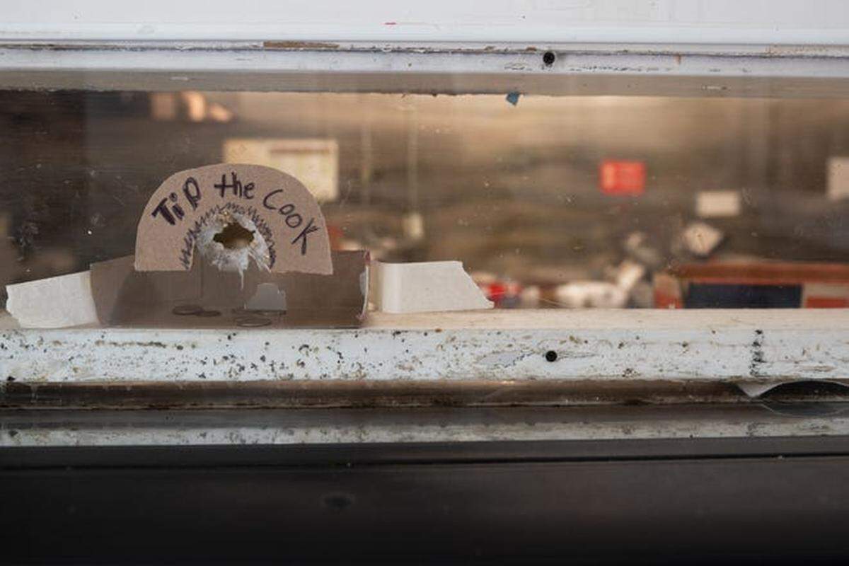At Charlie’s Convenient Market, the windows between the store owners and customers have bullet holes in them. Customers use one of the holes to slide in change.