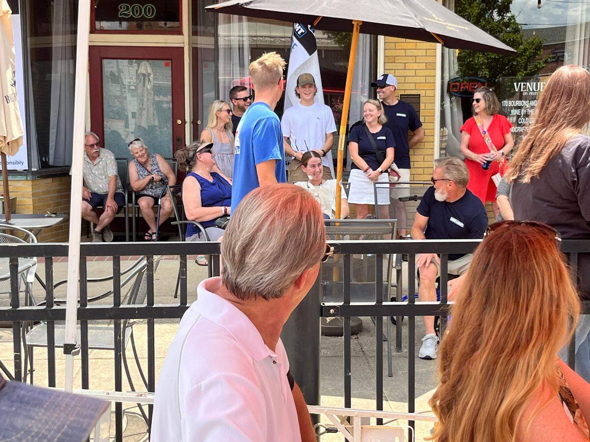 Injured Fairview Heights police officer Molly Muennich, seated at umbrella table in white shirt, reacts to praise from speakers at Rock the Blue, a fundraiser on Saturday in downtown Belleville.