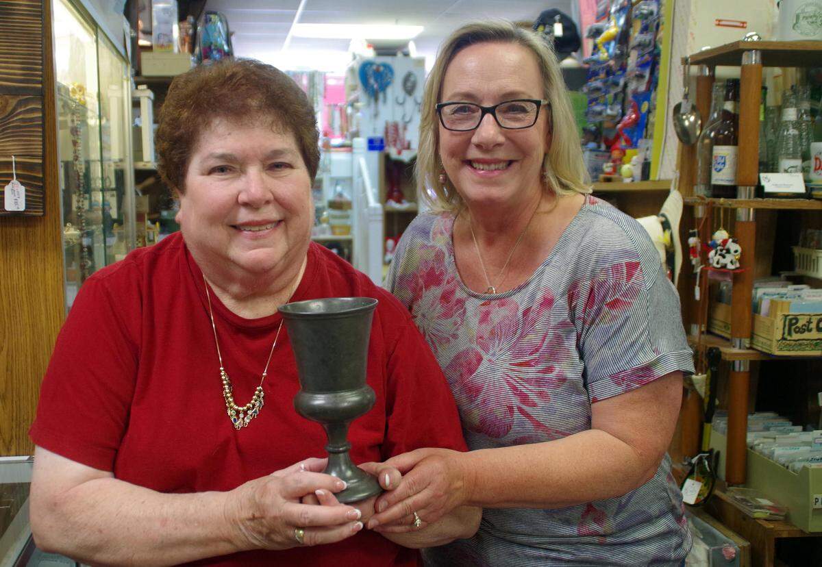 Former Mascoutah resident Rita Johnson, left, and Minnesota antique dealer Barb Urlaub pose with a pewter communion chalice that Johnson’s family possessed for 123 years.