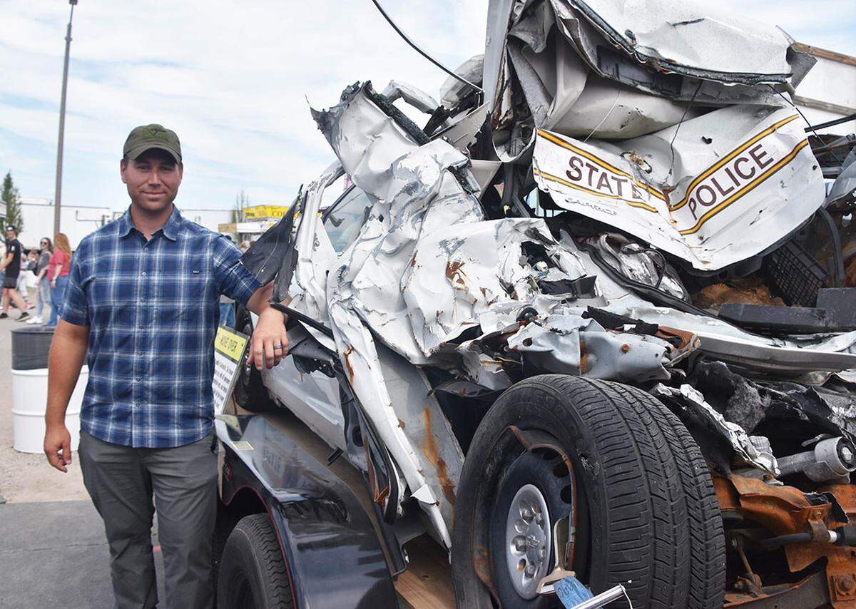 Trooper Alex Womack stands beside his wrecked squad. Womack sustained arm, leg and back injuries and required more than a year off work to recover.