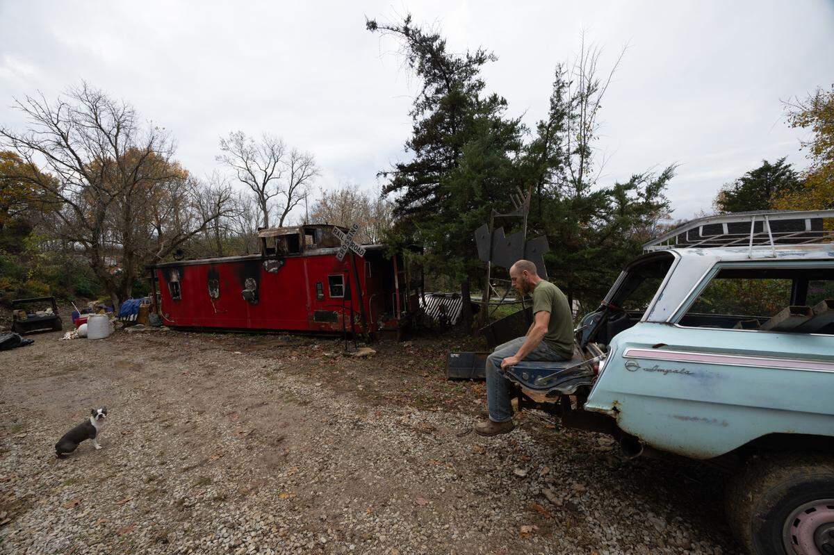 Jason Euge sits on the edge of his Chevrolet Impala at his property near Columbia, IL, and mourns the loss of his father, Robert, who died in a fire Saturday.