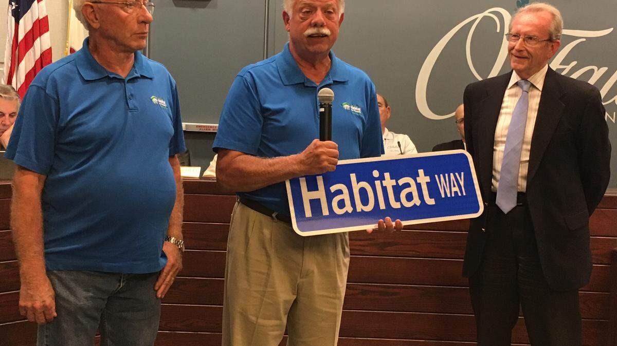 Habitat for Humanity O’Fallon Chapter Board members Lloyd Soeters, construction chair, and Jimmy Campbell, vice chair receive a street sign from Mayor Herb Roach.