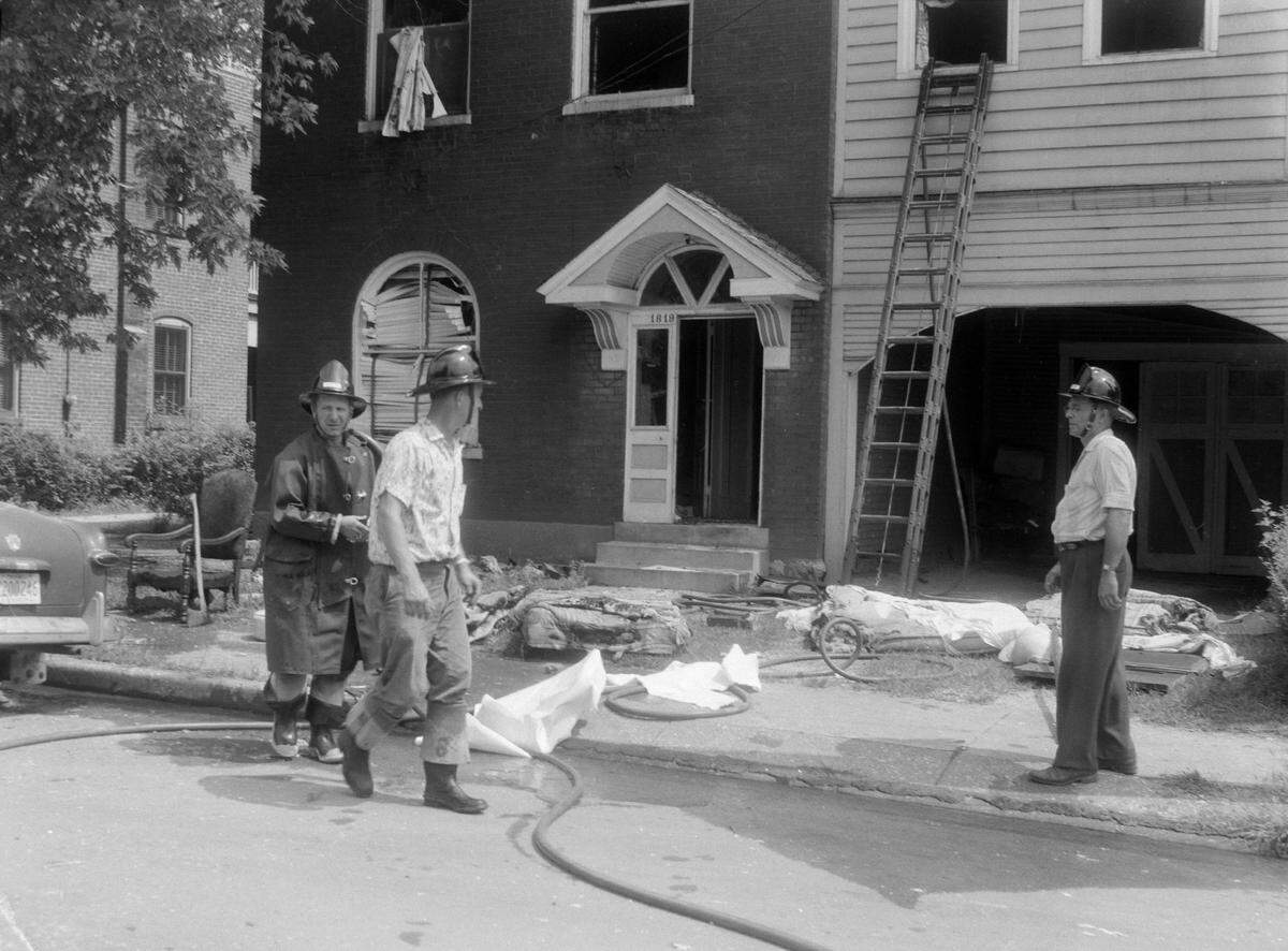 Belleville firemen stand outside the home of Steve Renneker on West Main Street, Belleville. The windows and doors were blown out of the house and its contents were set on fire after propane gas entered the water supply in July 1958. The home was vacant at the time of the explosion.
