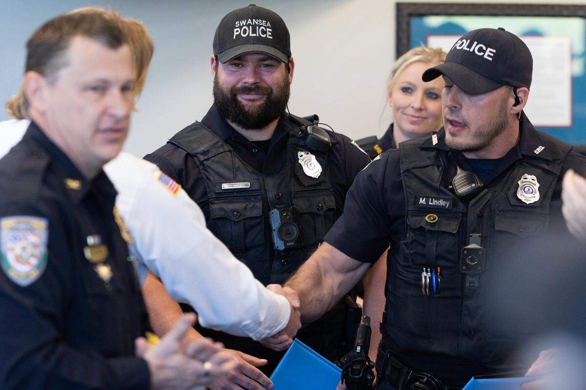 Justin Schutzbach, Matt Lindley and Breanna Kemper-Dunn, officers for the Swansea Police Department, shake hands with Swansea Fire Chief Doug Little during an awards ceremony recognizing their bravery for kicking in a garage door to save a man trapped in a house fire.