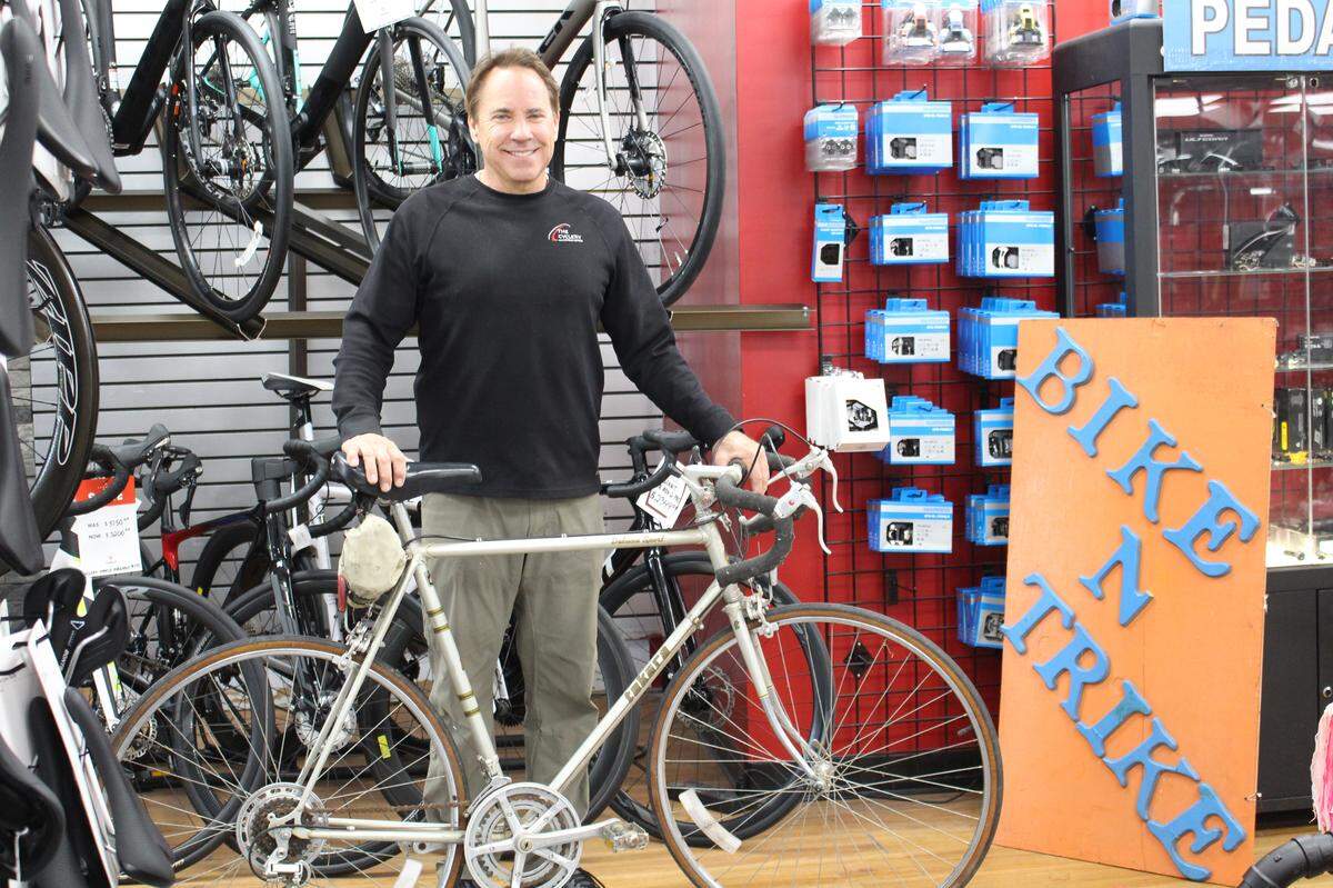 The Cyclery owner Steve Parks poses with a wooden sign from the late 1970s, when his business was called “Bike N Trike,” and one of the early Takara bicycles that he sold.