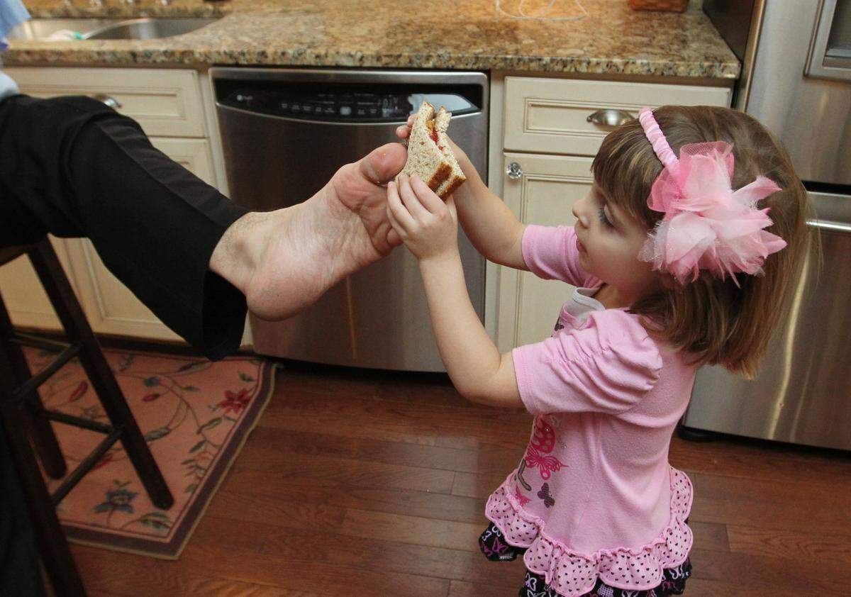 John Foppe gives his 4-year-old daughter, Faith, a peanut butter and jelly sandwich as an after-school snack.
