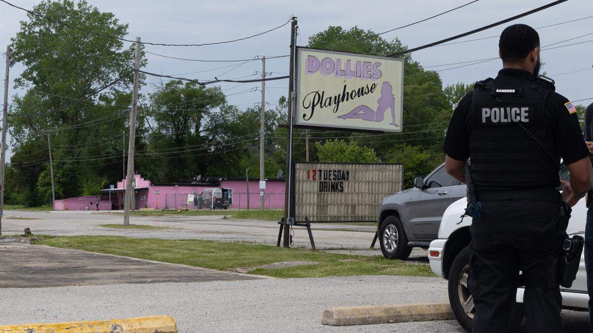 An officer for Washington Park stands in front a sign for Dollies Playhouse, a club in Washington Park, on May 2, 2024.