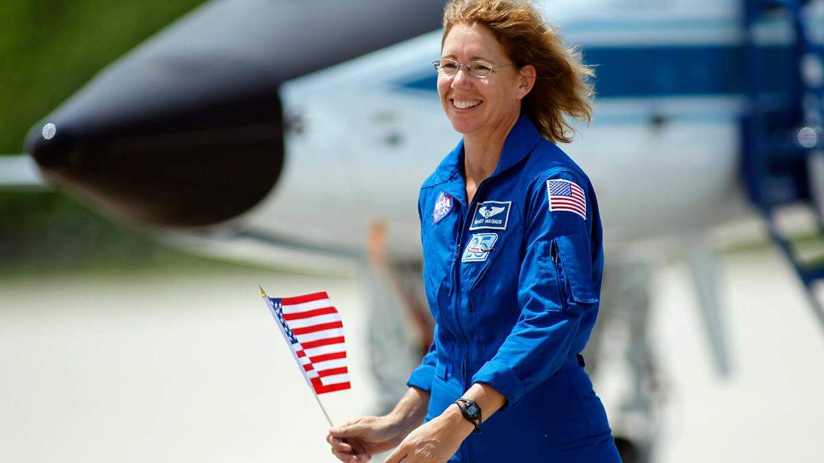 STS-135 mission specialist Sandy Magnus holds a U.S. flag as she walks across the tarmac after arriving with the rest of the crew at the Kennedy Space Center in Cape Canaveral, Fla., Monday, July 4, 2011. Space shuttle Atlantis, and her crew of four astronauts, is scheduled to lift off Friday morning on an 12-day mission to the international space station. The launch bring an end to NASA’s shuttle program. (AP Photo/Terry Renna)