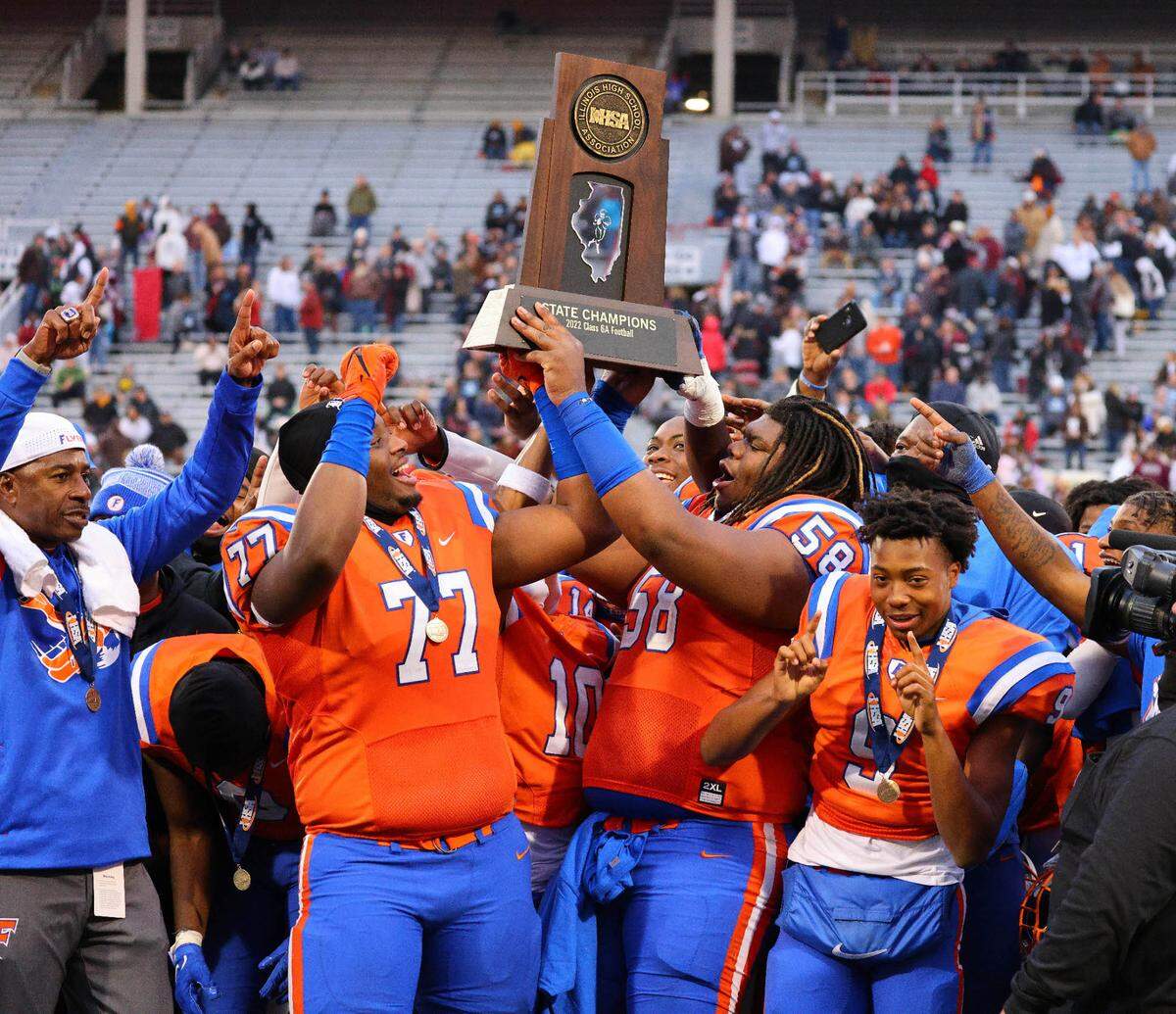East St. Louis’ Brandon Henderson and Miles McVay raise the championship trophy after a 57-7 victory against Prairie Ridge in the IHSA Class 6A state championship game Saturday at Memorial Stadium on the campus of the University of Illinois in Champaign. The Flyers captured their 10th state title while finishing the season with 11-straight wins and a 12-2 record.