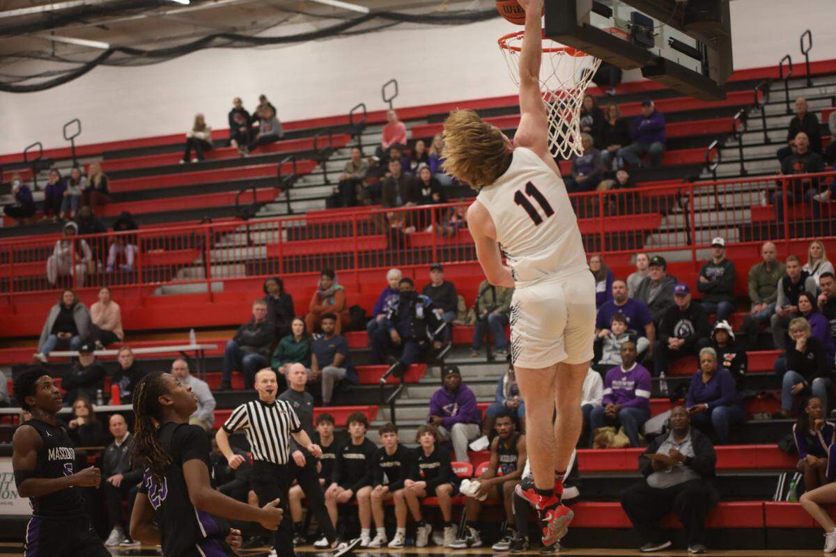 Highland junior guard Jake Ottensmeier goes up for a dunk over Mascoutah’s Michael Fox during a Mississippi Valley Conference game Friday, Jan. 13, at Highland High School. The Bulldogs ultimately posted a 51-45 victory.