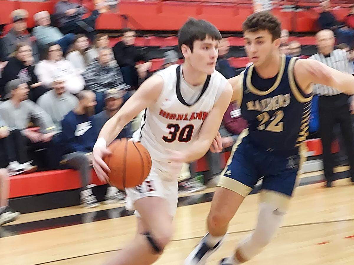 Highland sophomore forward Grant Fleming drives the baseline past Quincy Notre Dame senior forward Alex Connoyer during the second game of the 31st annual Highland Optimist Scott Credit Union Shootout on Saturday, Jan. 7. The Bulldogs ultimately posted 56-54 victory.