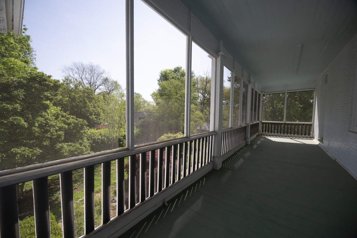 The second floor is home to a massive screened-in balcony, where the owner and guests can take in the serenity of the backyard garden below.