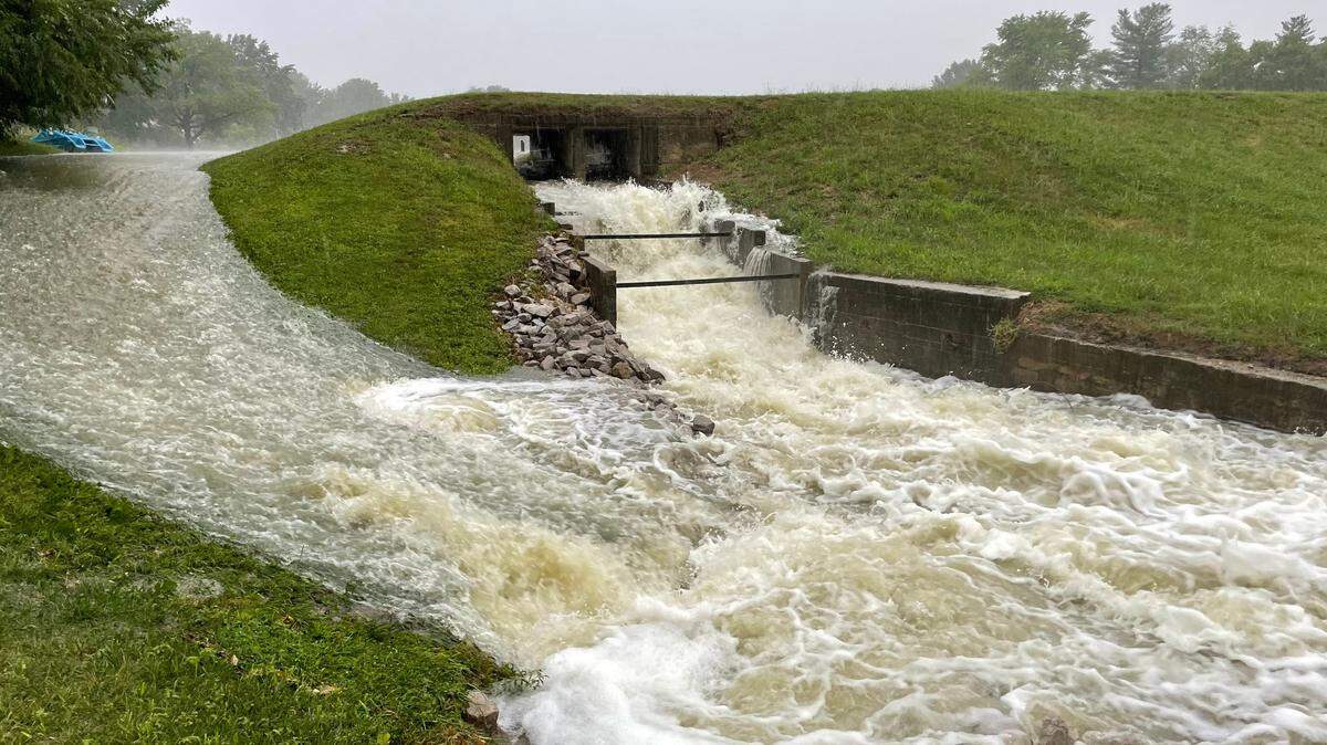 Water gushes through a spillway and into a storm water creek through the back yards of residents below Lake Yoch in Swansea.