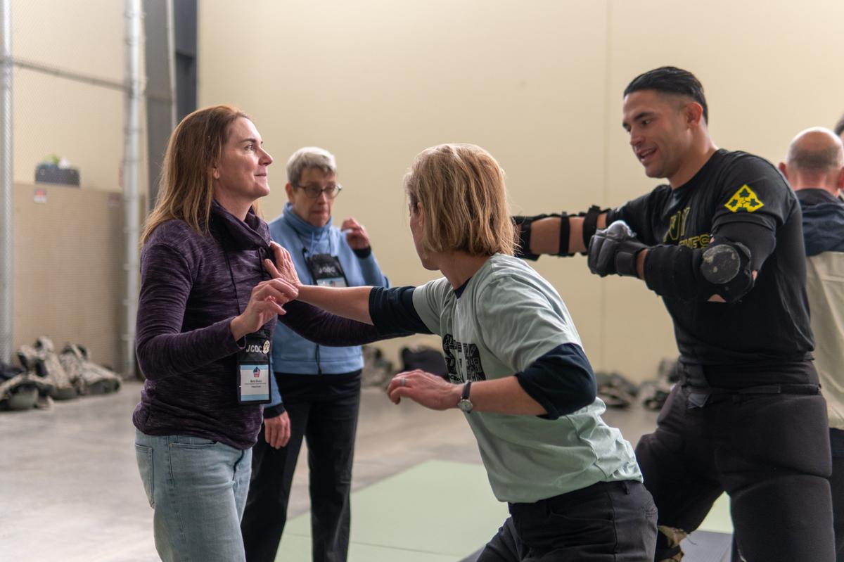 During the 93rd Joint Civilian Orientation Conference, Dr. Kelly Remijan, center, received a hands-on demonstration of Army combatives training at Fort Carson, Colorado, on Oct. 25. Nominated by the 375th Air Mobility Wing, Remijan, a professional development and curriculum specialist for the Illinois Math and Science Academy, was one of nearly 40 business, academic, and community leaders from across the U.S. selected to participate in the conference.