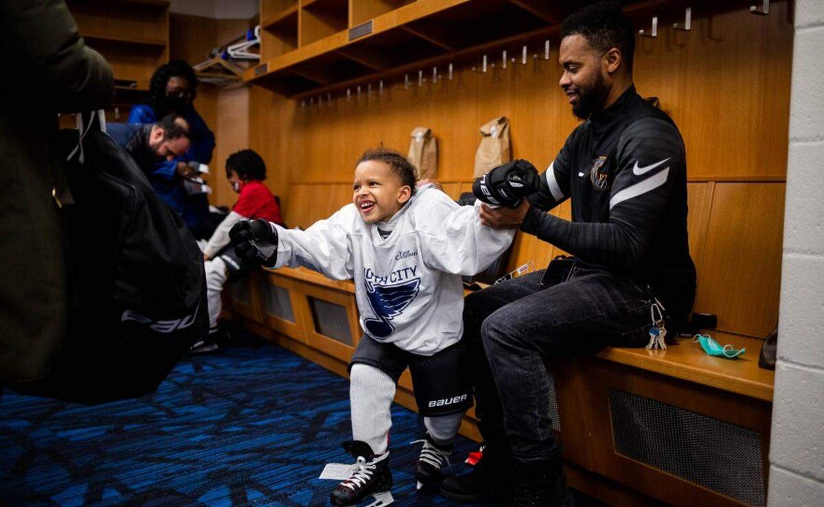 David Shanks, right, of north St. Louis, adjusts gloves on Daxton Shanks, his 4-year-old son, March 9 during a North City Blues practice at the Enterprise Center. Brittanie Shanks, Daxton’s mother, stands to the left.