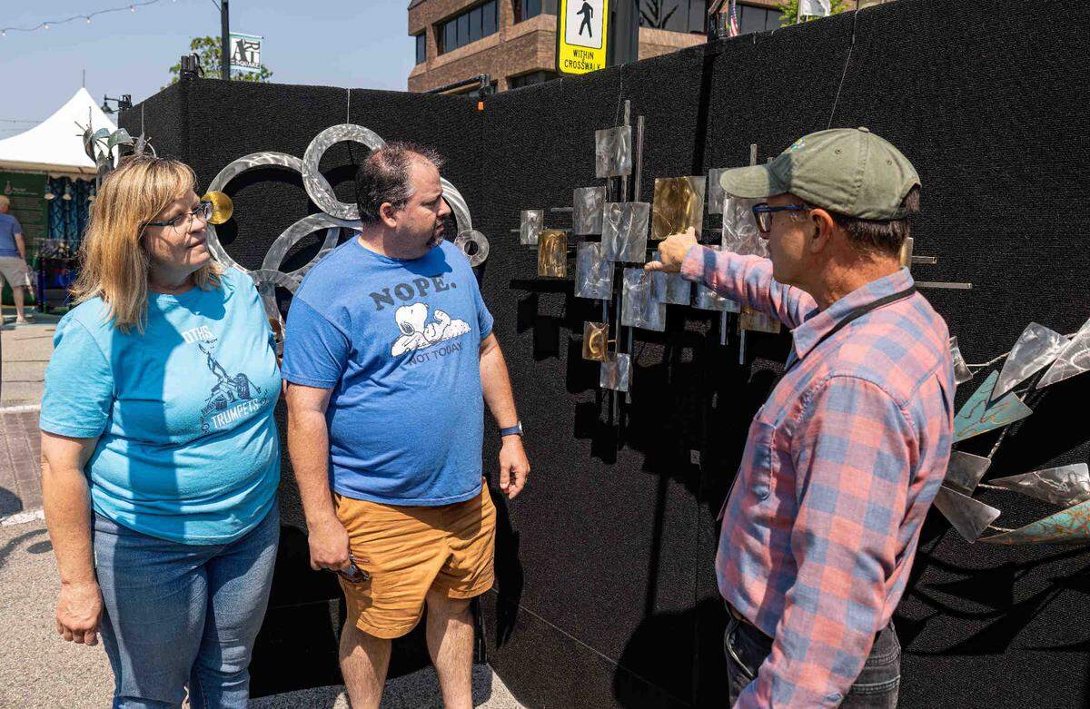 Artist Ron Stinson, from Carlisle, Pennsylvania, explains his Metal Art Expressions work to Jon and Michelle Burgmann, of O’Fallon, during the Art on the Square show Saturday.