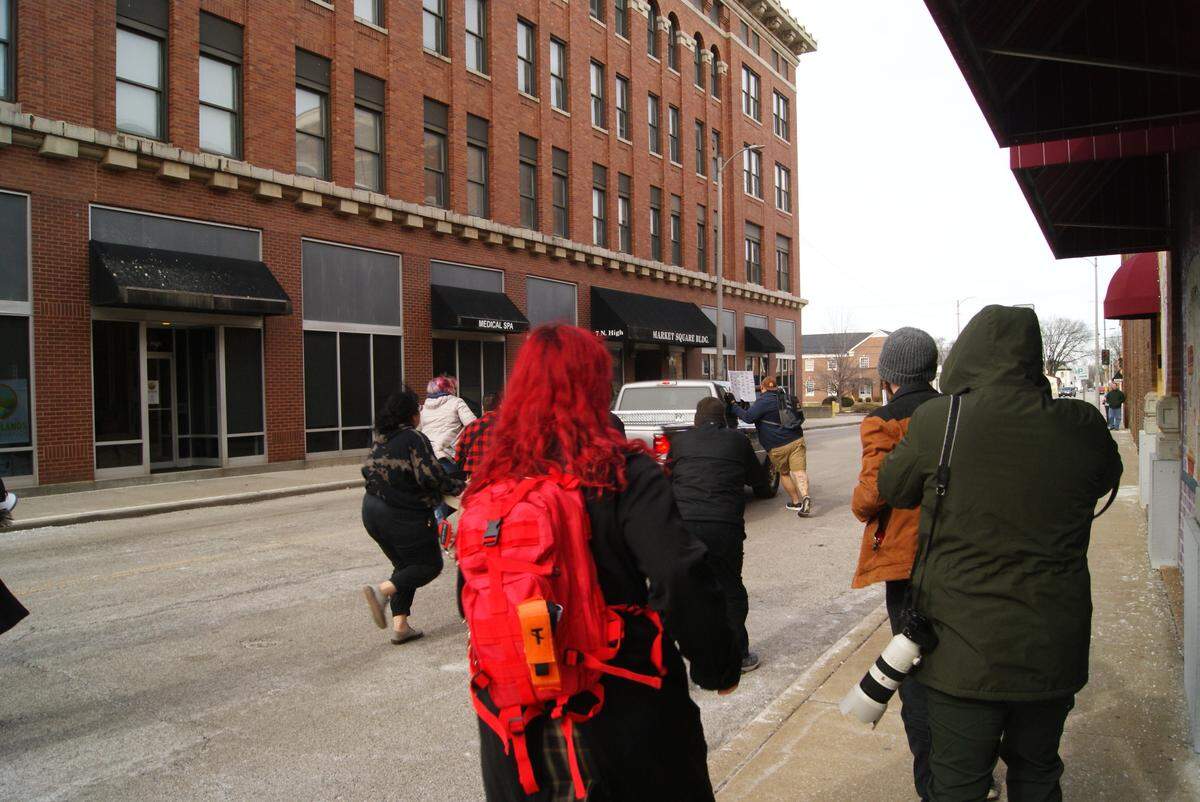 Protesters ran after a truck on North High Street after it had driven through a group of protesters at the corner of North High and East Main streets in downtown Belleville Saturday. One of the protesters had grabbed onto the back of the truck and then fell to street as the truck pulled away.