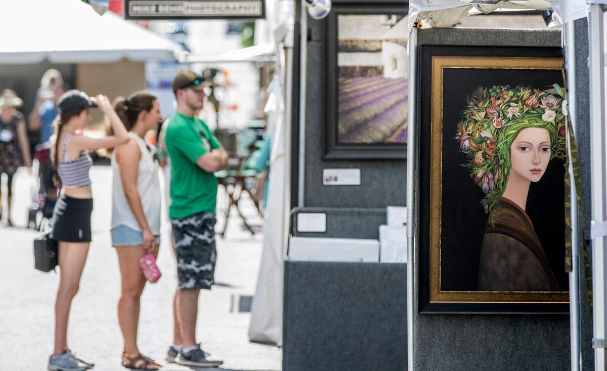 Visitors look at Michael Behr photography at Art on the Square in Belleville in 2019, the last “normal” year before COVID-19 forced cancellation of one festival and postponement of another.