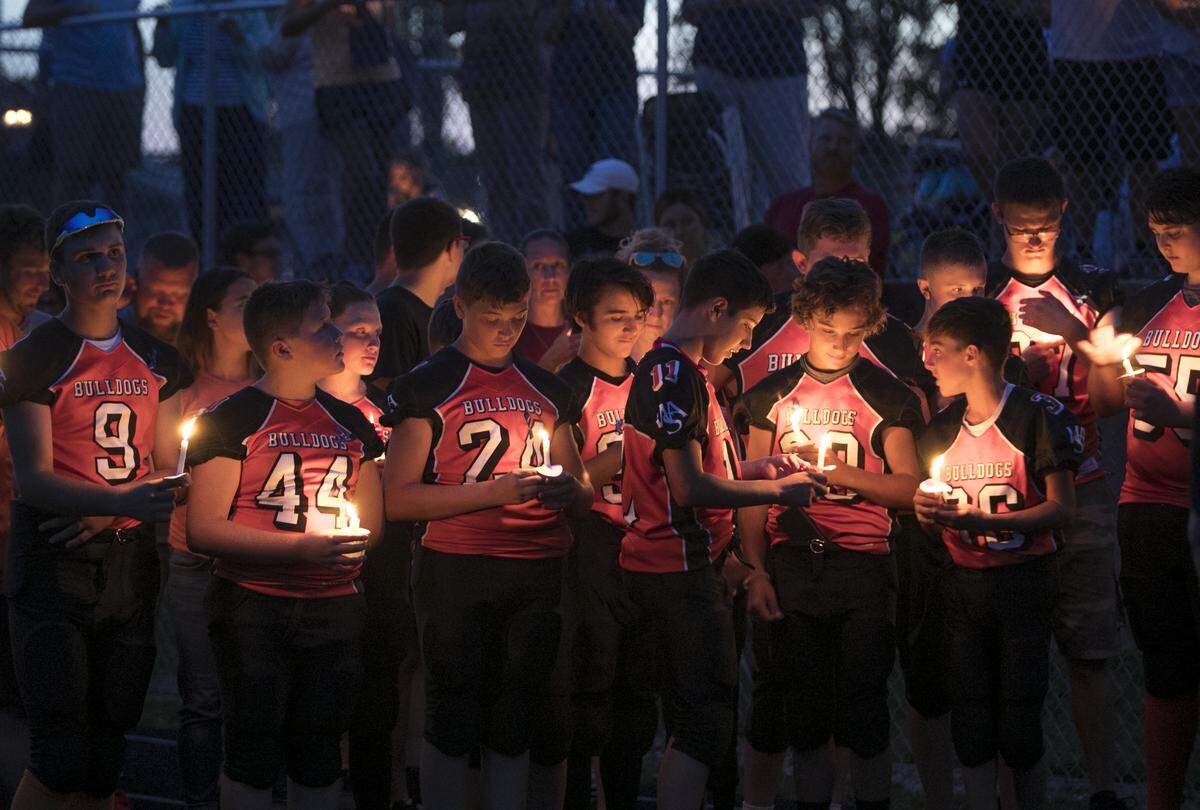 Several hundred people attend a candlelight vigil to show their support for Trooper Nicholas Hopkins and his family Thursday on the old Waterloo High School football field.