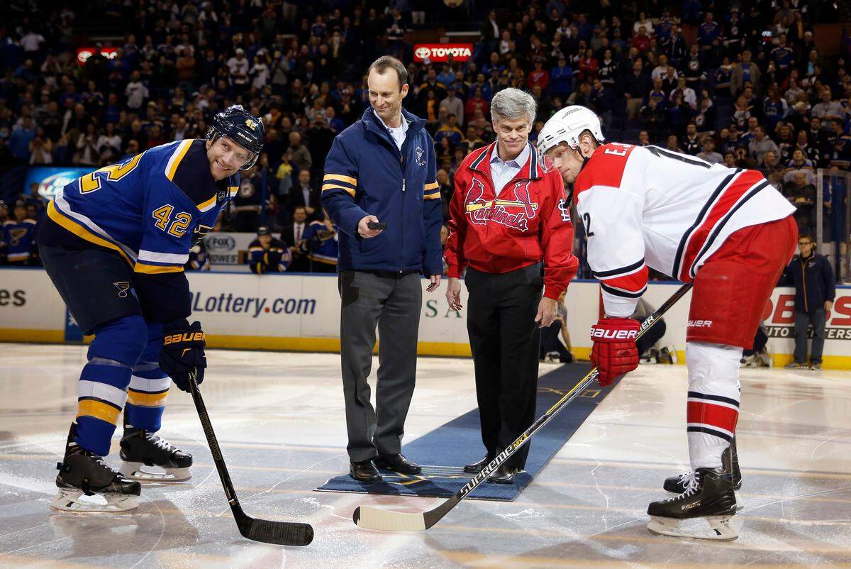 St. Louis Cardinals president Bill DeWitt III, second from left, prepares for a ceremonial puck drop alongside St. Louis Blues owner Tom Stillman as Blues’ David Backes, left, and Carolina Hurricanes’ Eric Staal, right, wait before an NHL hockey game on Thursday, Jan. 14, 2016. The image set a powerful message to St. Louis sports fans after Stan Kroenke and the NFL Rams departed to Los Angeles. (AP Photo/Jeff Roberson)