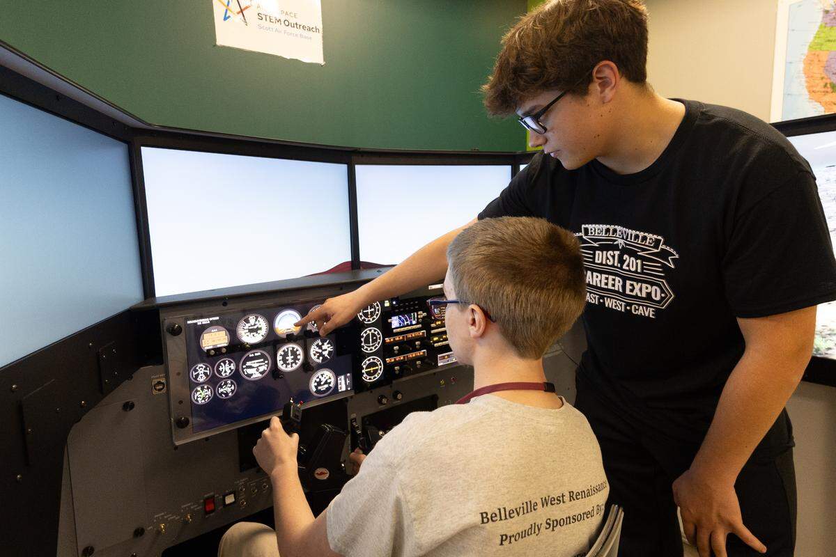 Kaleb Pfeil shows fellow Belleville West student Michael Tiren how to operate a flight simulator during a career exposition at The CAVE.