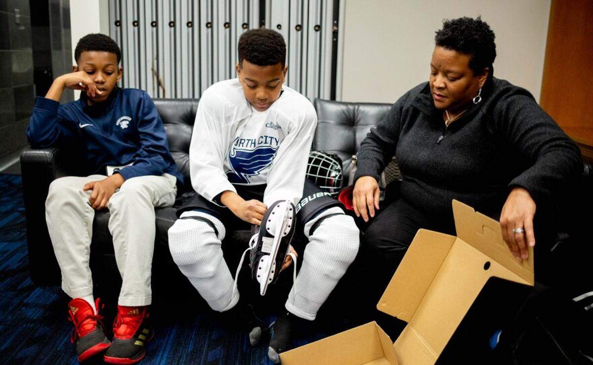Matthias Thompson, 12, center, of north St. Louis, puts on skates alongside his brother, Nate Thompson, left, 12, and mother Treena Thompson, right, on March 9 at the Enterprise Center.