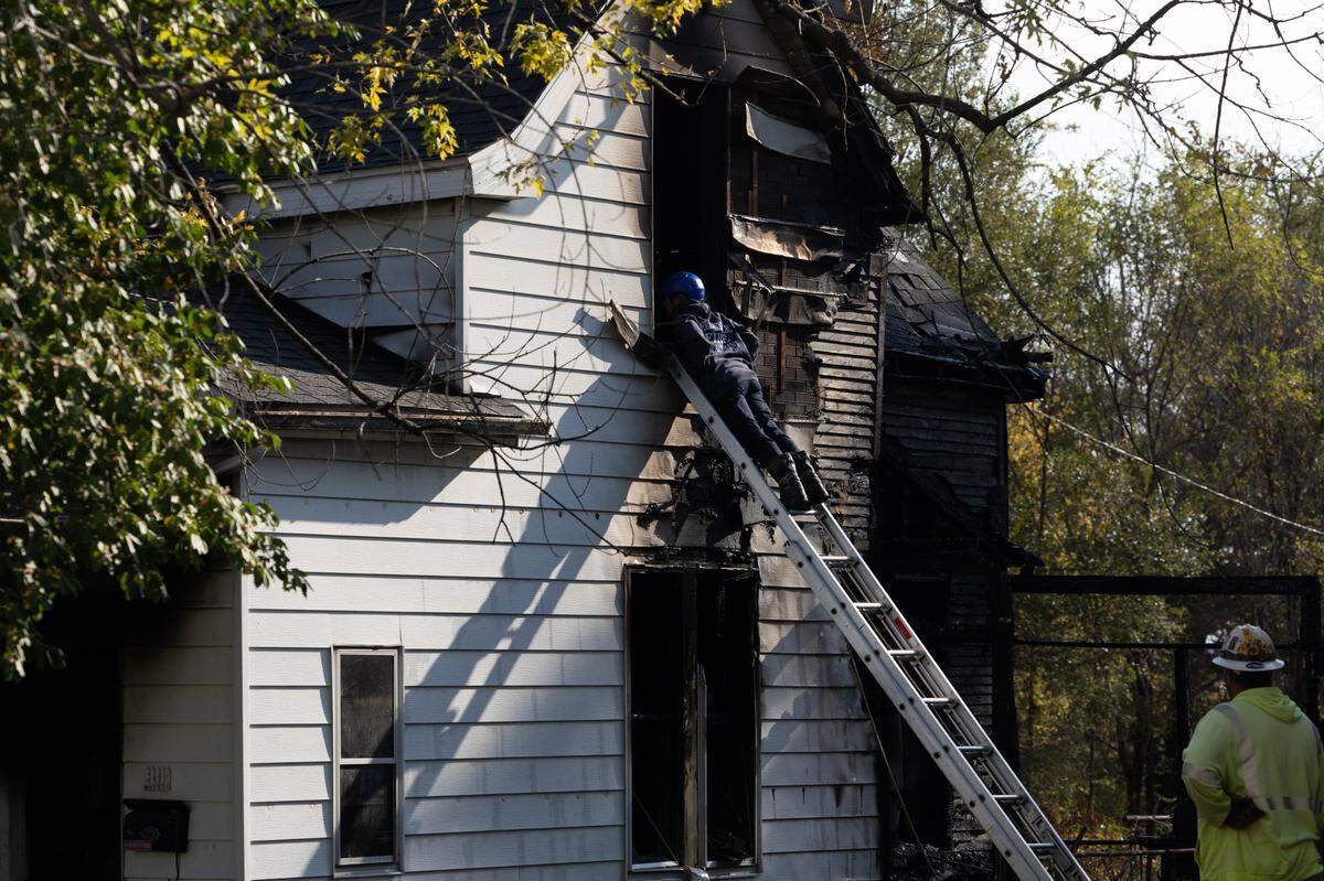A Belleville Firefighter looks into the second-floor window of a burned out house on South 13th Street Monday morning. At least one person has been confirmed dead.