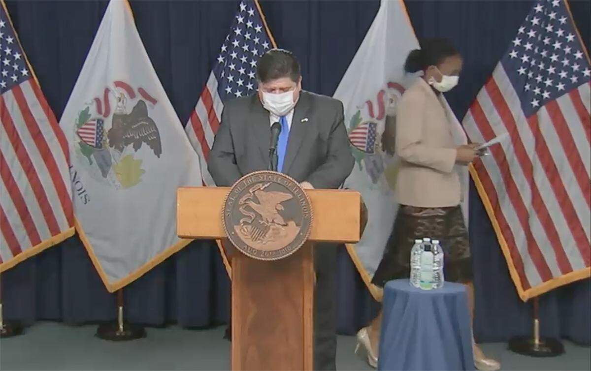 Gov. J.B. Pritzker and Illinois Department of Public Health Director Dr. Ngozi Ezike wear masks as they arrive for a daily coronavirus press briefing in Chicago on April 5, before the state began requiring people to wear them in public.