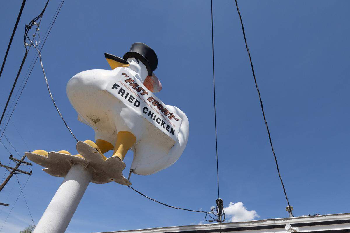 The front of Fast Eddie’s Fried Chicken boasts a large chicken statue wearing a top hat.