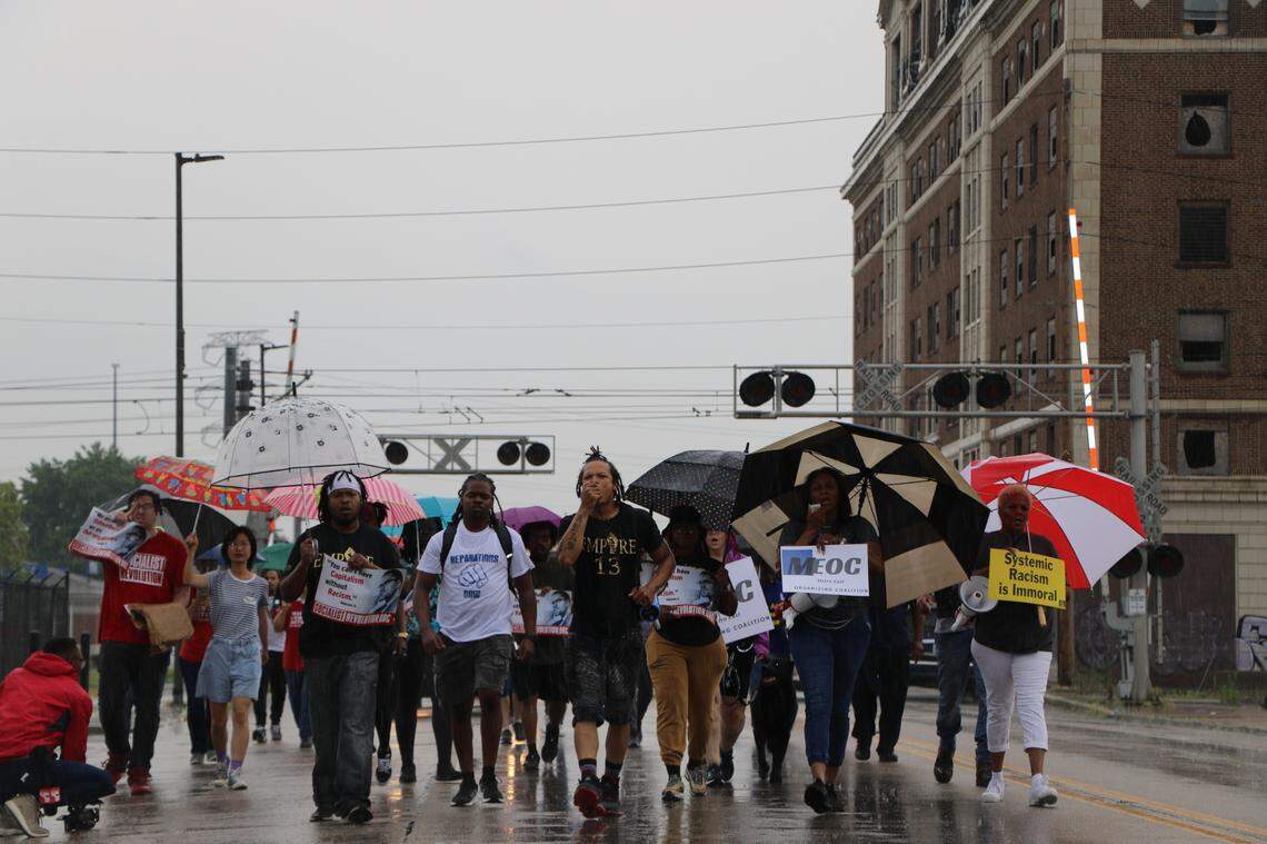 Marchers walk through the rain down East Broadway on Saturday in East St. Louis to remember the victims of the 1917 massacre and call on government leaders for reparations.