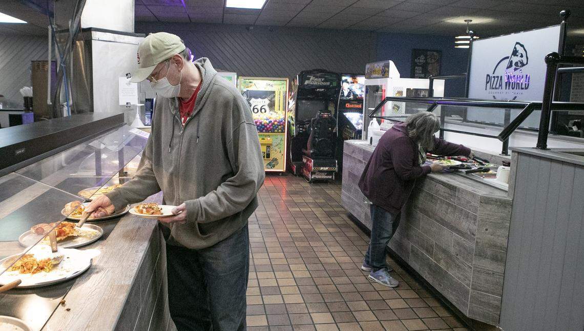 Roger WIllette and Susan Willette help themselves to the buffet lunch at Pizza World in Granite City Monday. Several restaurants in Granite City and across the metro-east have opened their dining rooms to customers on Monday despite state restrictions that prohibit it due to the COVID-19 pandemic.