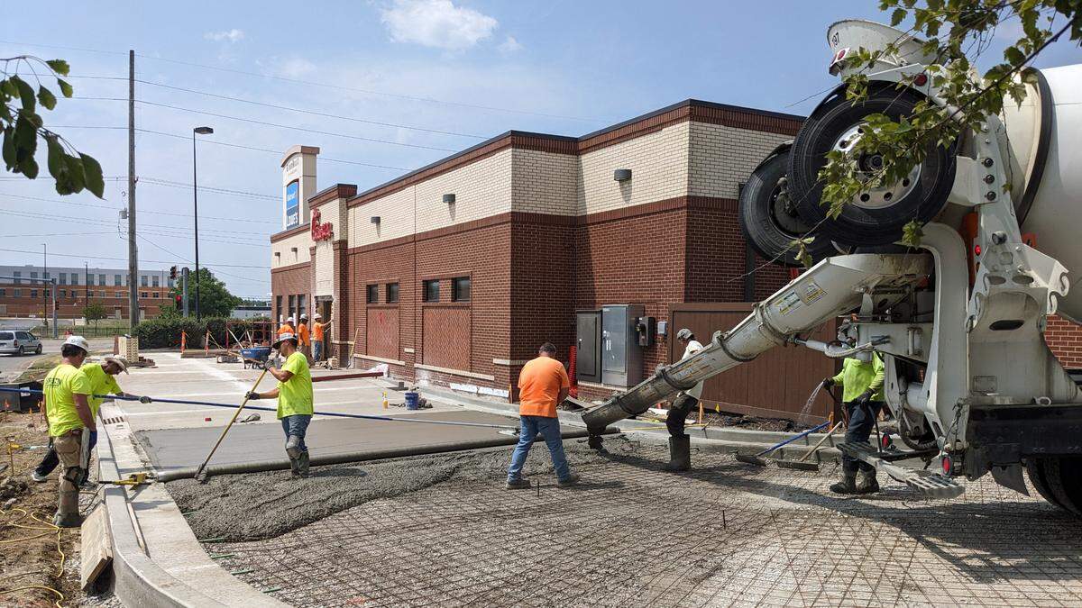 View of crew members pouring concrete for the drive-thru as brickwork is done in the background at Chick-fil-A in Belleville