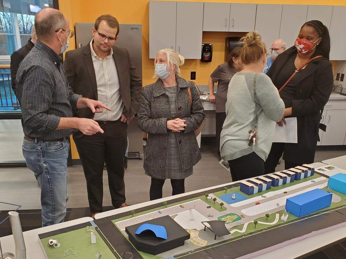 Art Village co-founder David Kniepkamp, left, answers questions at an open house held in December at The Rec in Fairview Heights. He’s standing next to a model that shows what the project could look like someday.