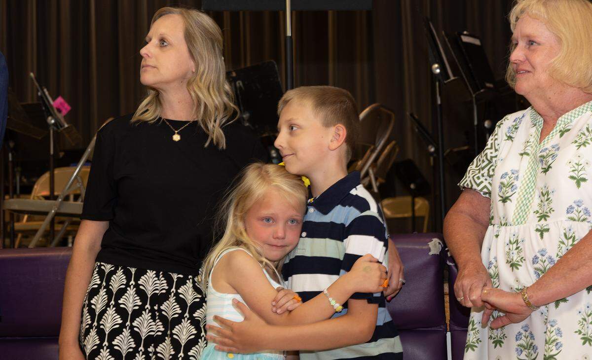 Josh Veath’s daughter Addy is held by her brother Braylon after her father won the prestigious Golden Apple Excellence in Teaching Award.
