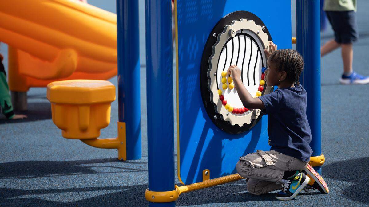 A child plays with a puzzle during a ribbon-cutting for Hinchcliffe elementary’s newly-opened inclusive playground. Part of the playground’s approach to inclusivity involves the installation of enriching activities that are accessible to children of all abilities.