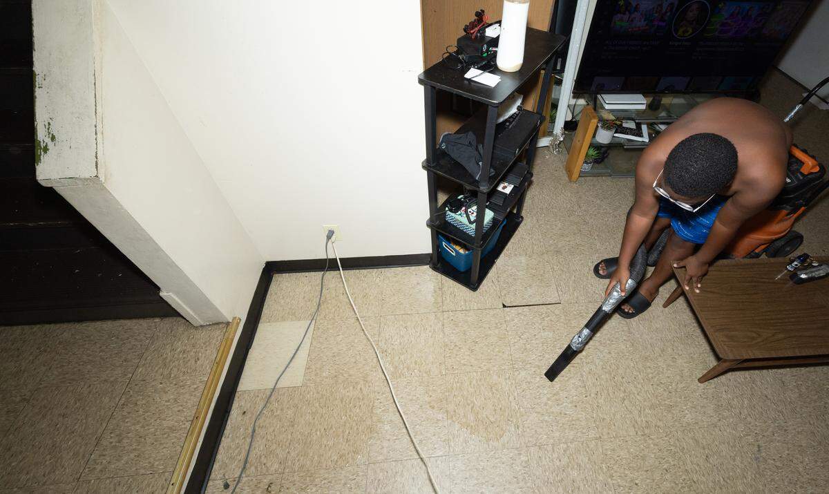 Isaiah Felton, 11, removes water flooding the living room of his and his mother’s home at Greystone Apartments on July 29, 2025.