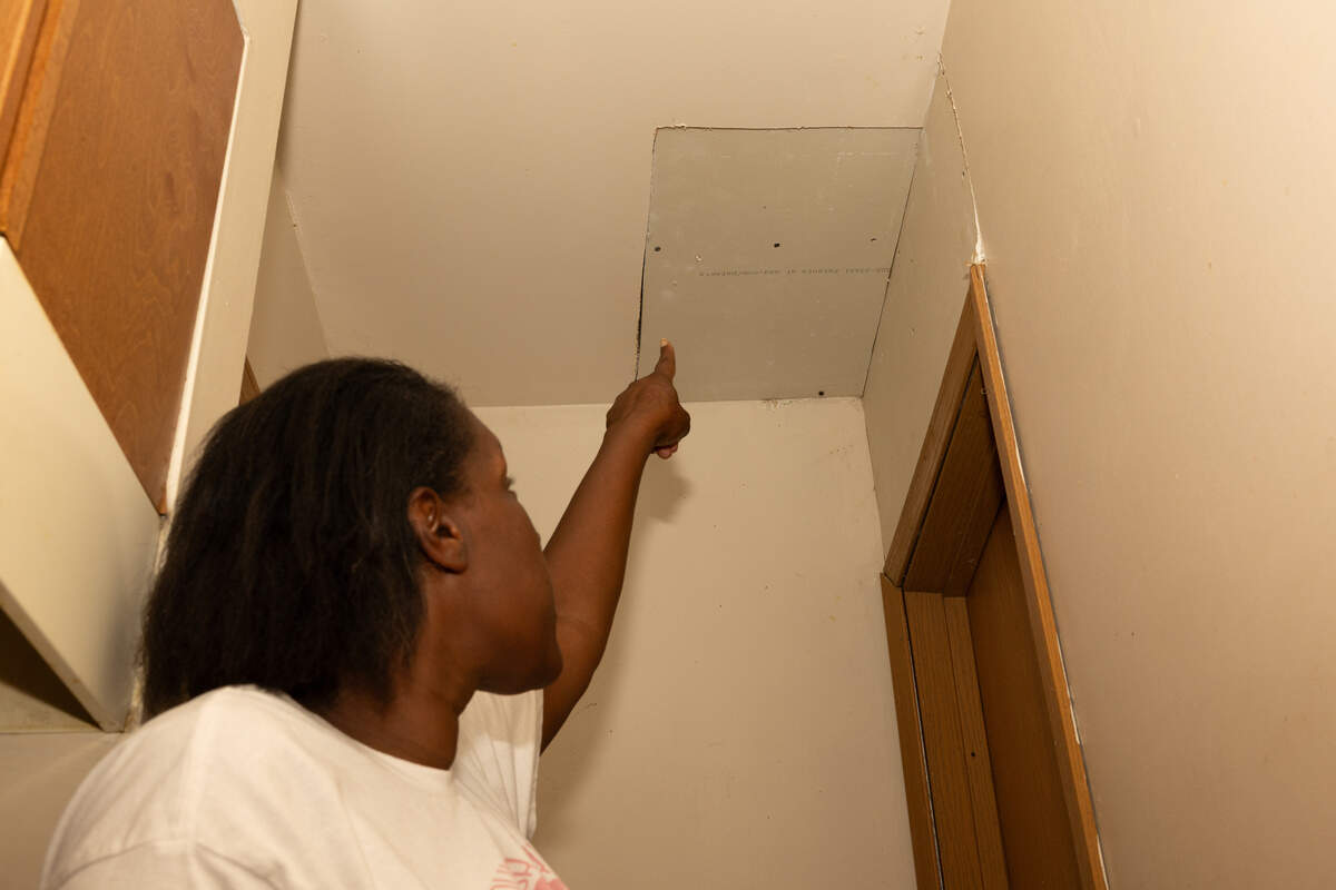 Twanna White points out a panel where water drips from the ceiling. White says management tried to fix it, but did a poor job.