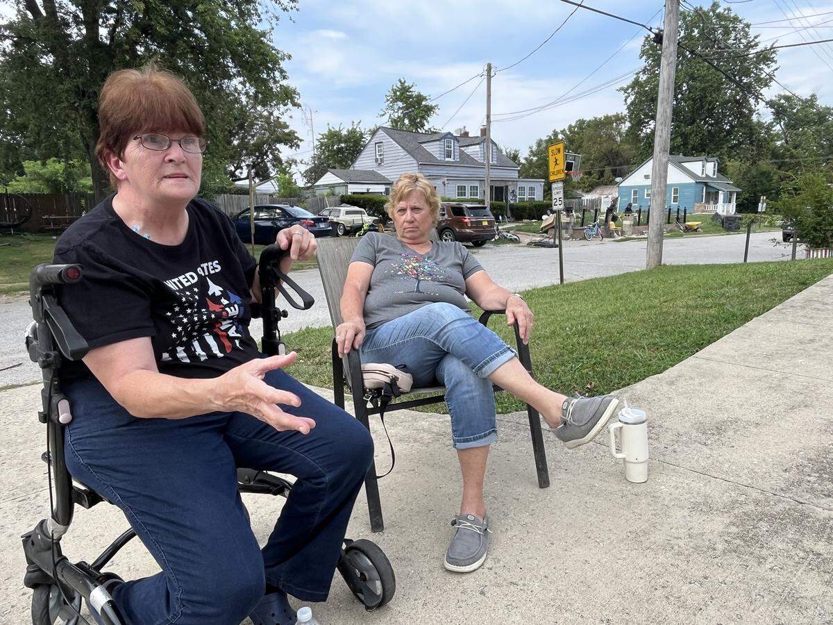 Kathy Draper, left, and her neighbor, Lana Brede, are shown sitting in Draper’s front yard last fall, across from a home on South 19th Street in Belleville that they consider an eyesore due to the vehicles, barbecue grills, furniture, lawn mowers, bicycles, construction materials, tools, appliances and trash that fill it.