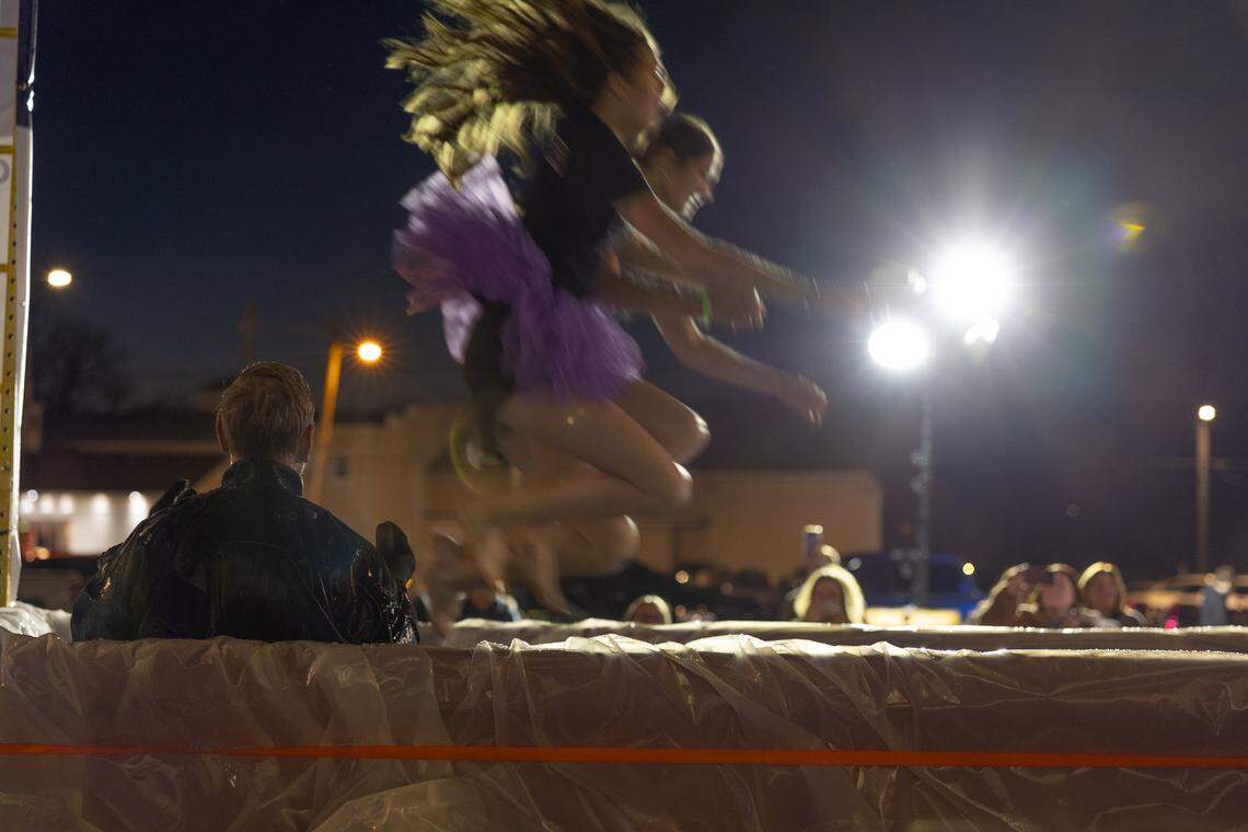 A pair of Collinsville High School Kahoks leap into a dumpster in support of the plunge while O’Fallon search-and-rescue divers watch Friday.