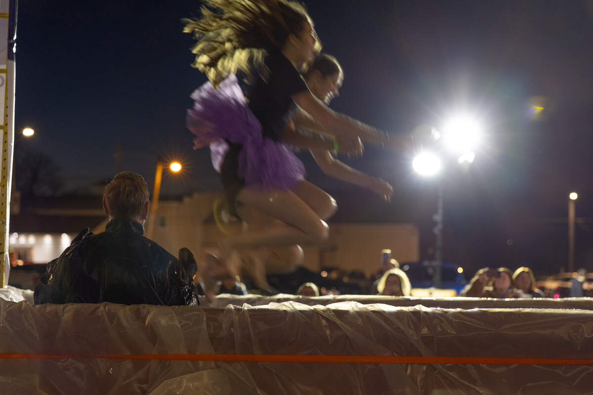 A pair of Collinsville High School Kahoks leap into a dumpster in support of the plunge while O’Fallon search-and-rescue divers watch Friday.