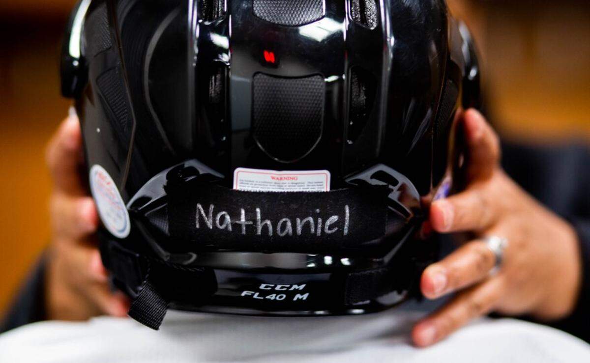 Treena Thompson, of north St. Louis, adjusts a helmet on the head of her son, Nate Thompson, 9, on March 9 before a North City Blues practice.