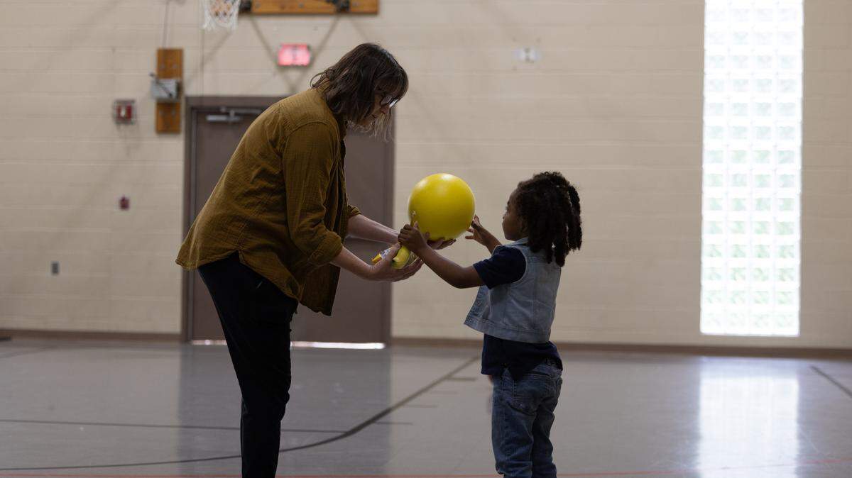 A volunteer at the Belleville drop-in center hands a ball to a child to play basketball with on Aug. 7, 2024.