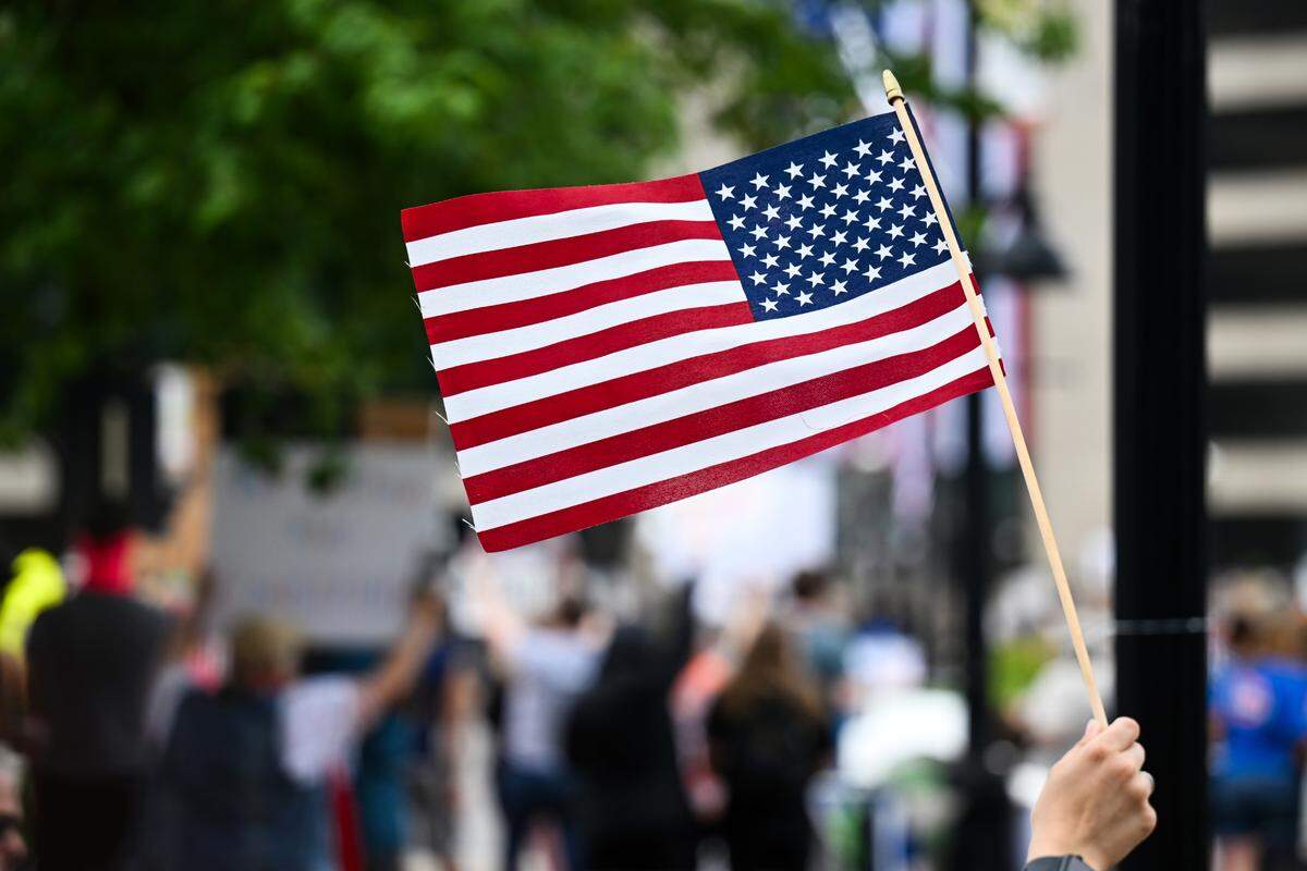 A “No Kings” protester in Belleville holds up an American flag.