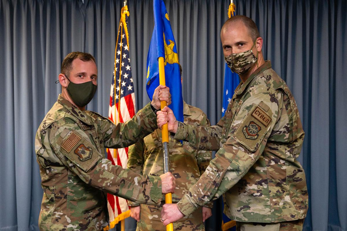 U.S. Air Force Lt. Col. Andrew Mackenzie, 375th Communication Squadron incoming commander, assumes command after receiving guidon from Col. Kyle Baldassari, 375th Communications Group commander, during an assumption of command ceremony on Scott Air Force Base. The 375th CS provides communications and computer systems used by Scott AFB and 31 tenant units.