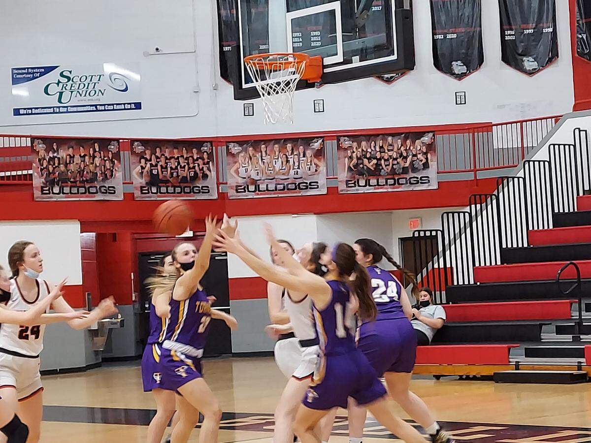Highland’s Larissa Taylor, left, and Emma Warner, right middle, stretch out to grab a loose ball in the consolation quarterfinals of the 35th annual Highland Tournament against Taylorville on Tuesday, Jan. 18, at Highland High School. The Lady Bulldogs cruised to a 51-36 victory.